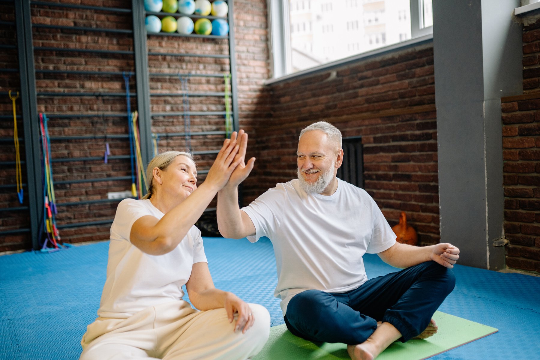 An Elderly Couple High Fiving each other while Sitting in the Gym